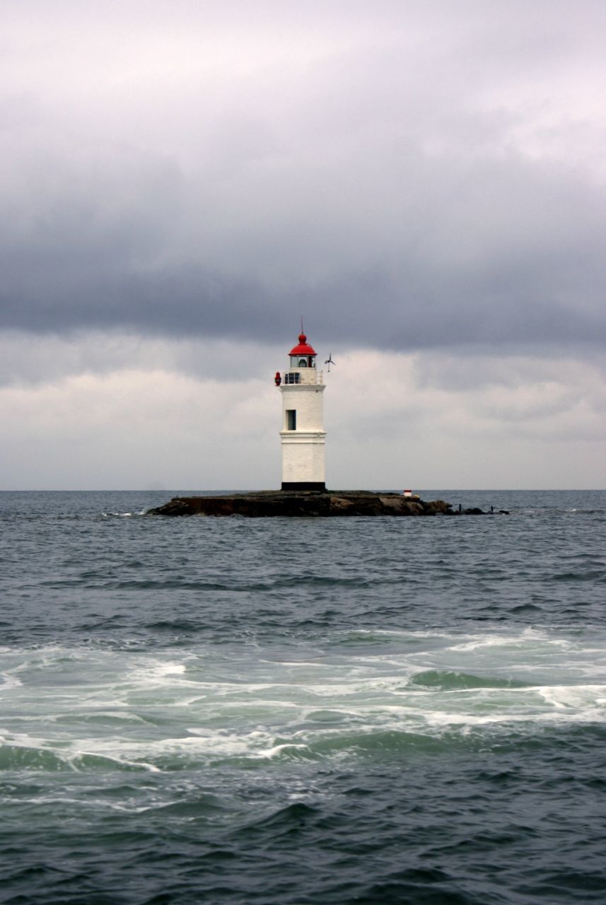 Low angle view of lighthouse amidst sea against cloudy sky