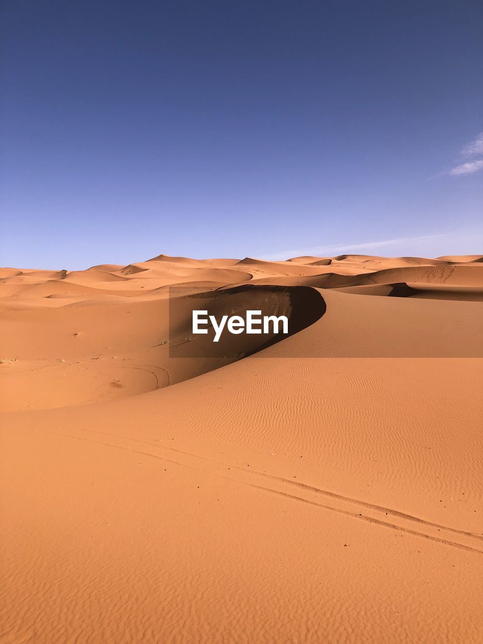 Sand dunes in sahara desert against clear blue sky