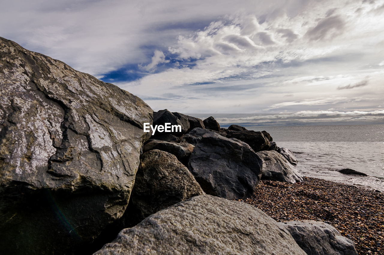 Rock formation on beach against sky