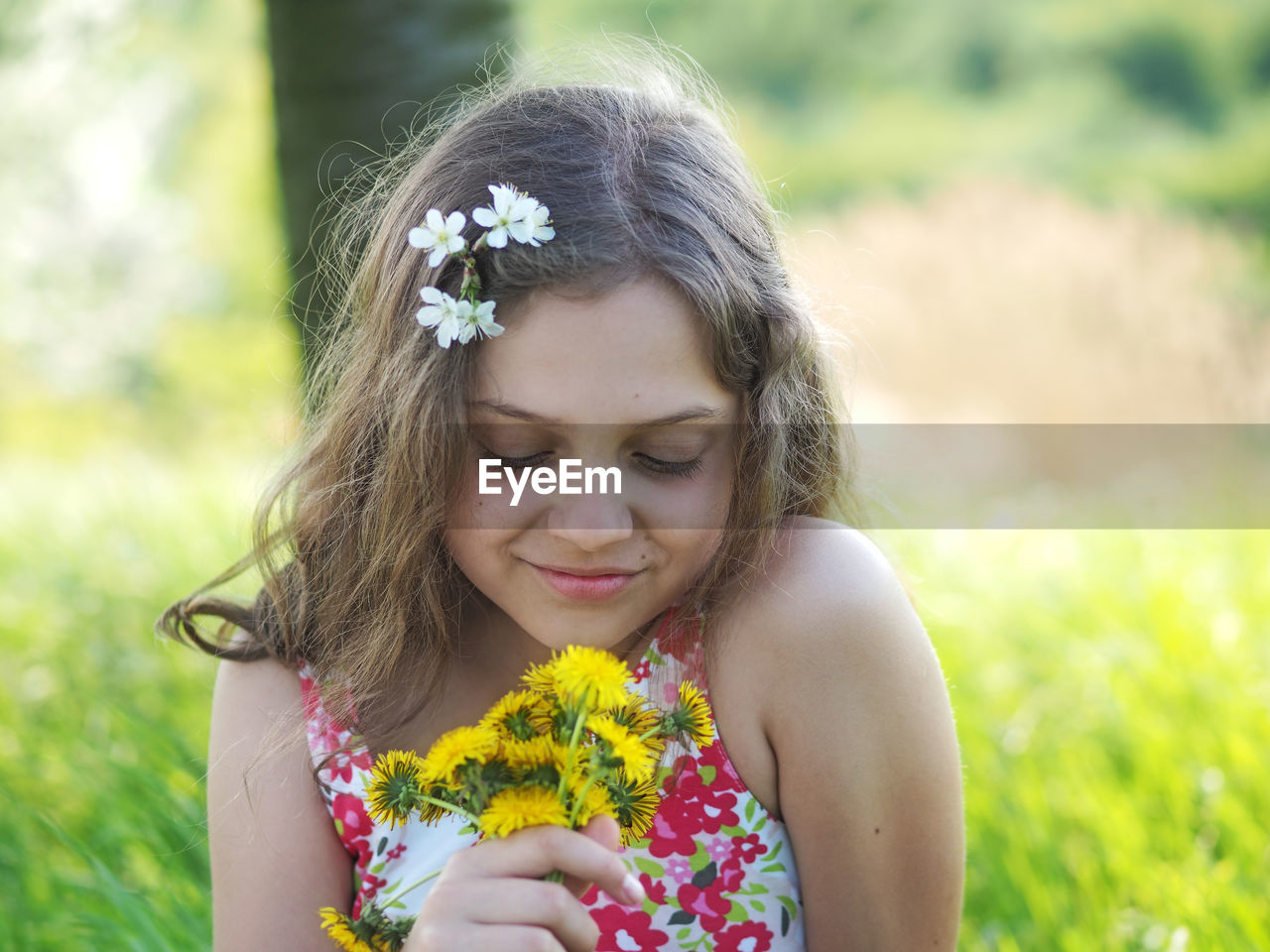 Close-up of girl holding yellow flowers at park