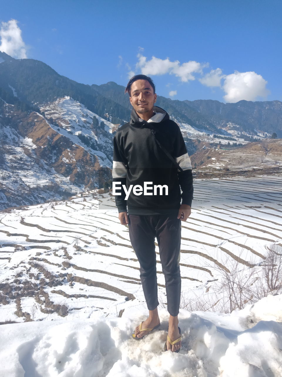 Portrait of man standing on snowcapped mountains during winter