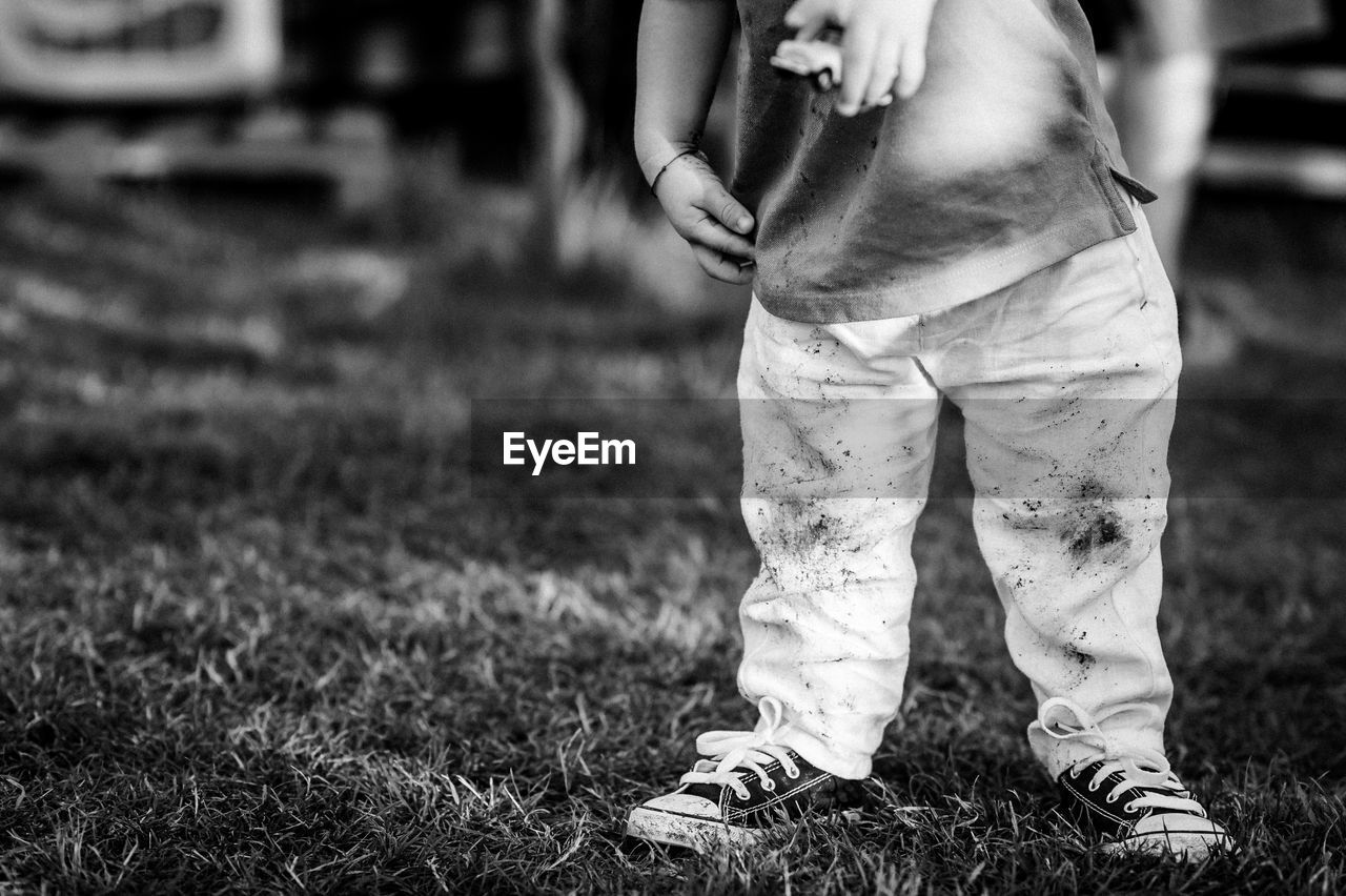 Low section of boy standing in grass