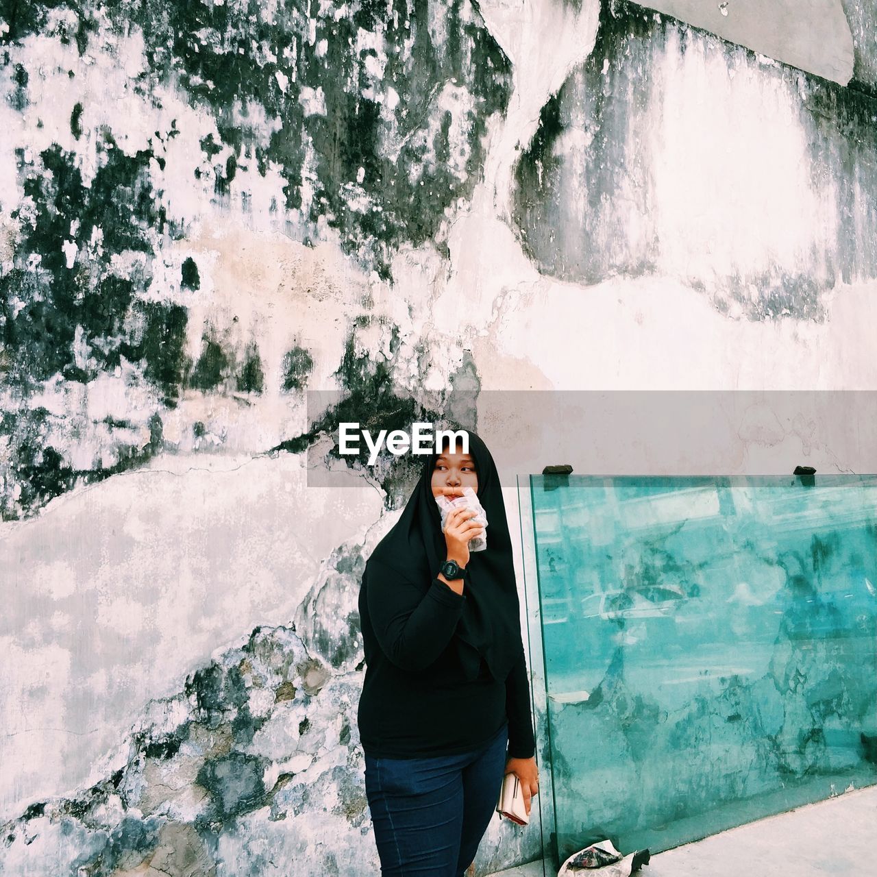 Young woman standing against building