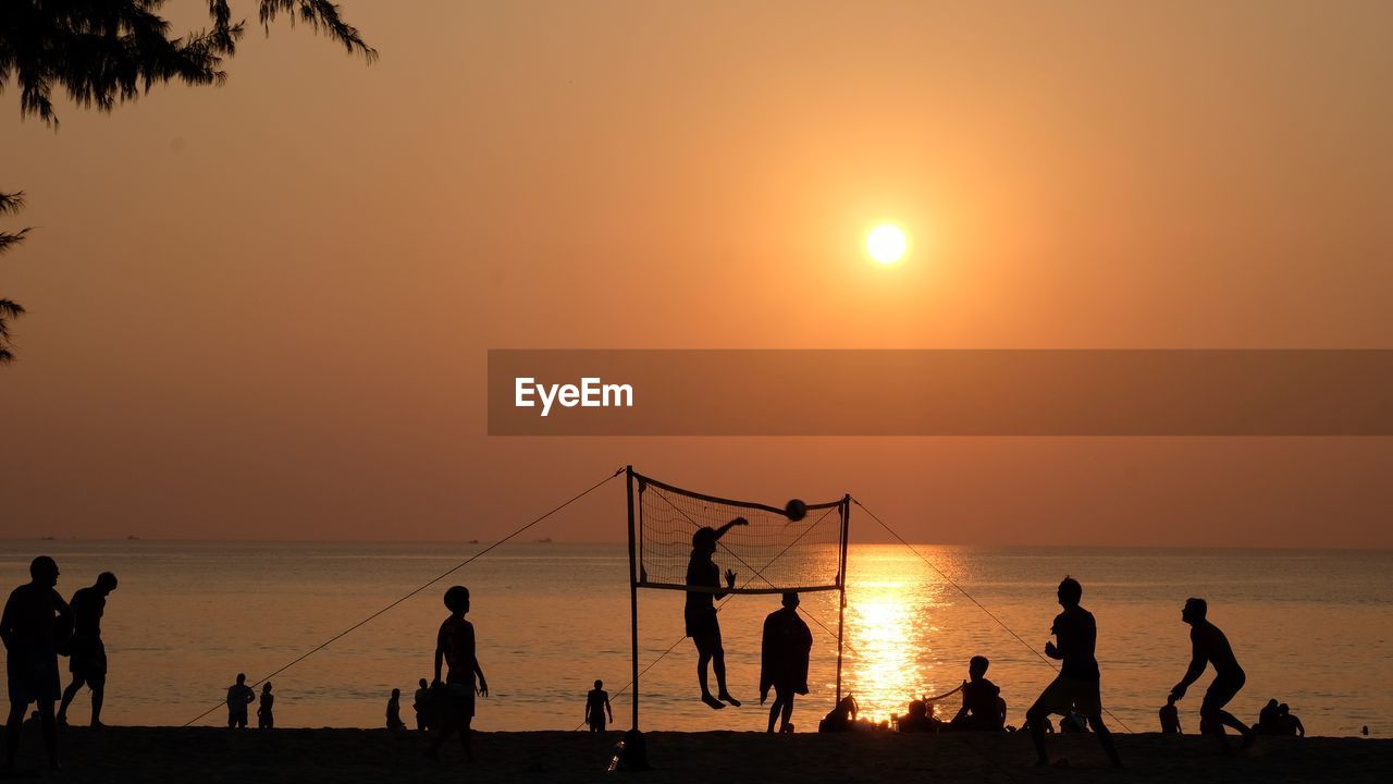 Silhouette people playing on beach against sky