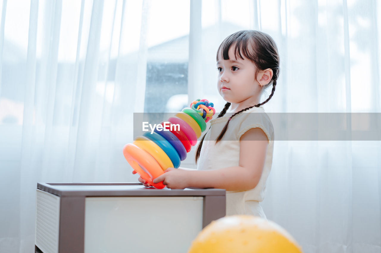 Girl playing with multi colored toys at home