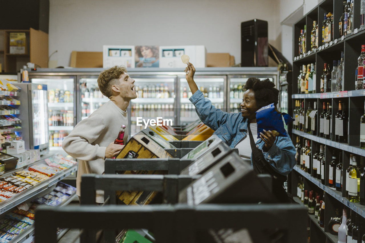 Playful couple having fun while doing shopping at supermarket