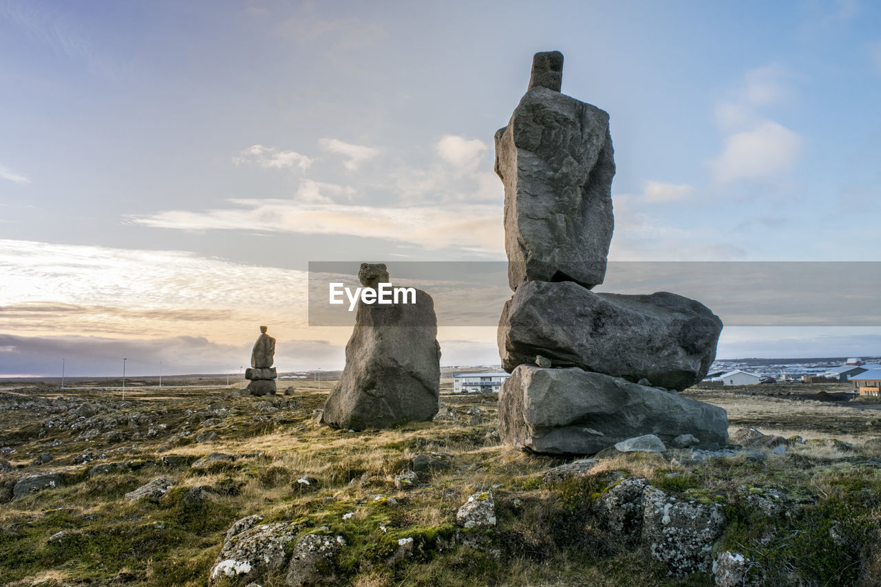 Stacked stones on field against sky