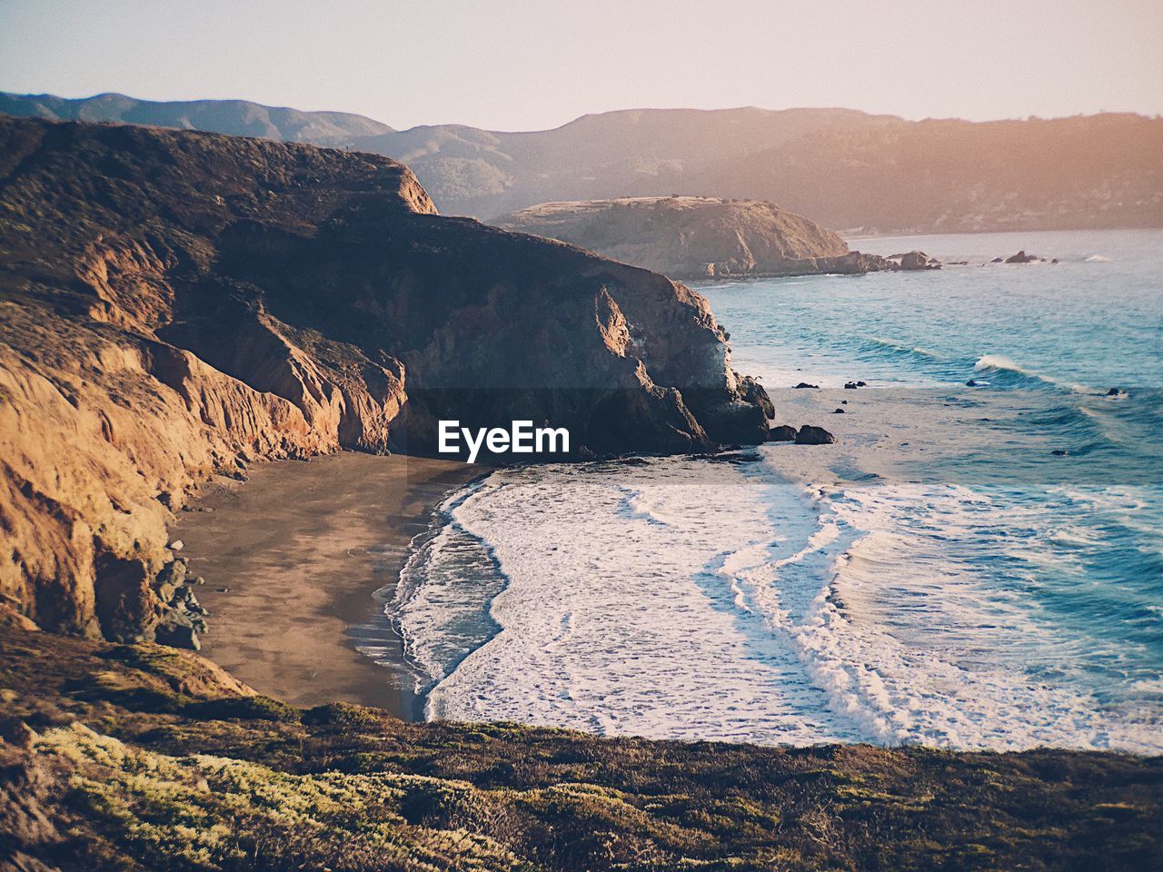 Scenic view of sea by mountains against sky