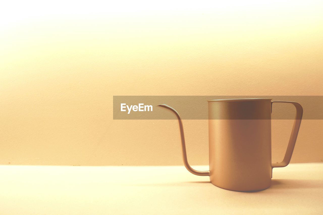 CLOSE-UP OF COFFEE CUP ON TABLE AGAINST WHITE BACKGROUND