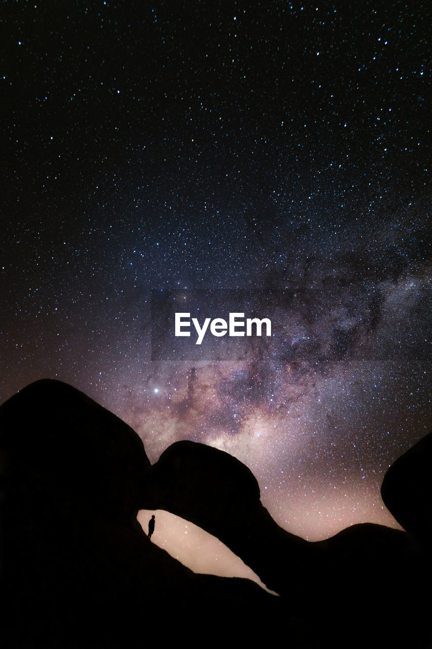 Low angle view of silhouette mountain against sky at night