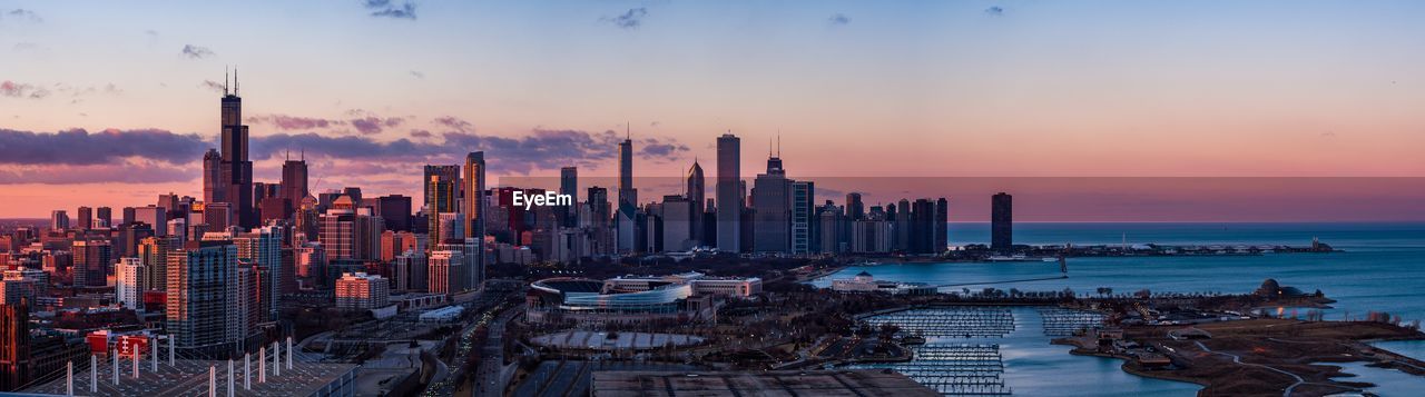 Panoramic view of sea and buildings against sky during sunset