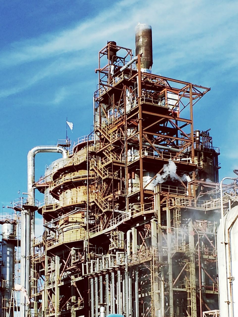 Low angle view of oil refinery against sky
