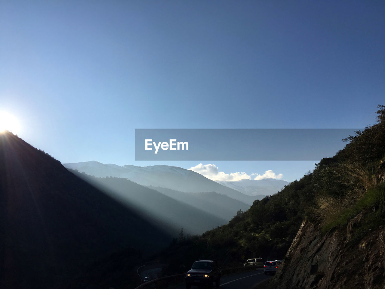 Cars on road at mountains against blue sky