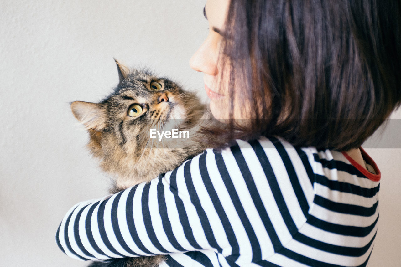 Close-up of woman holding cat against white background