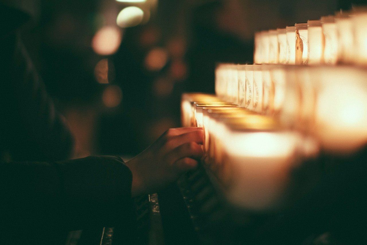 Cropped hand holding tea light candles at church