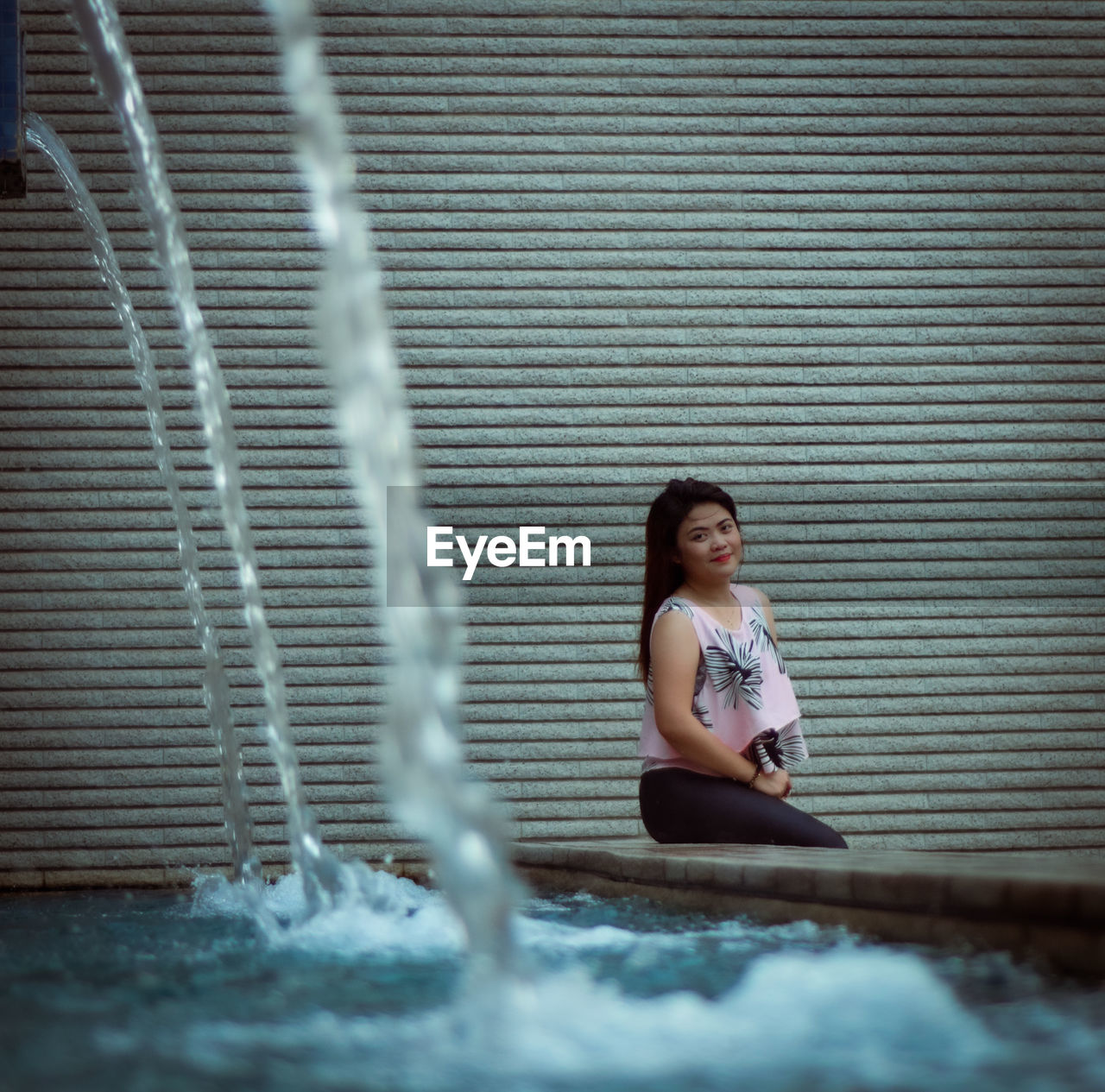 Portrait of young woman sitting by fountain