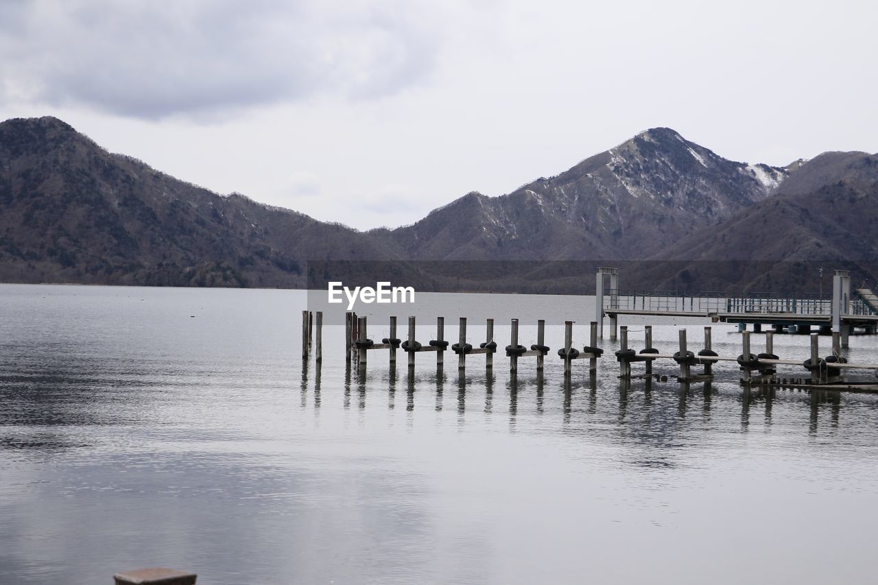 Wooden posts in lake against mountains