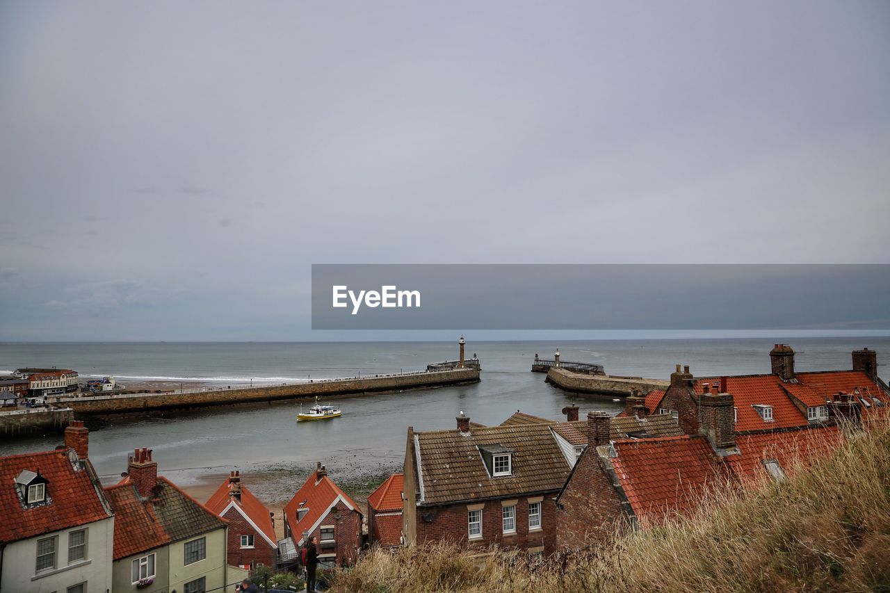 Houses by sea against sky