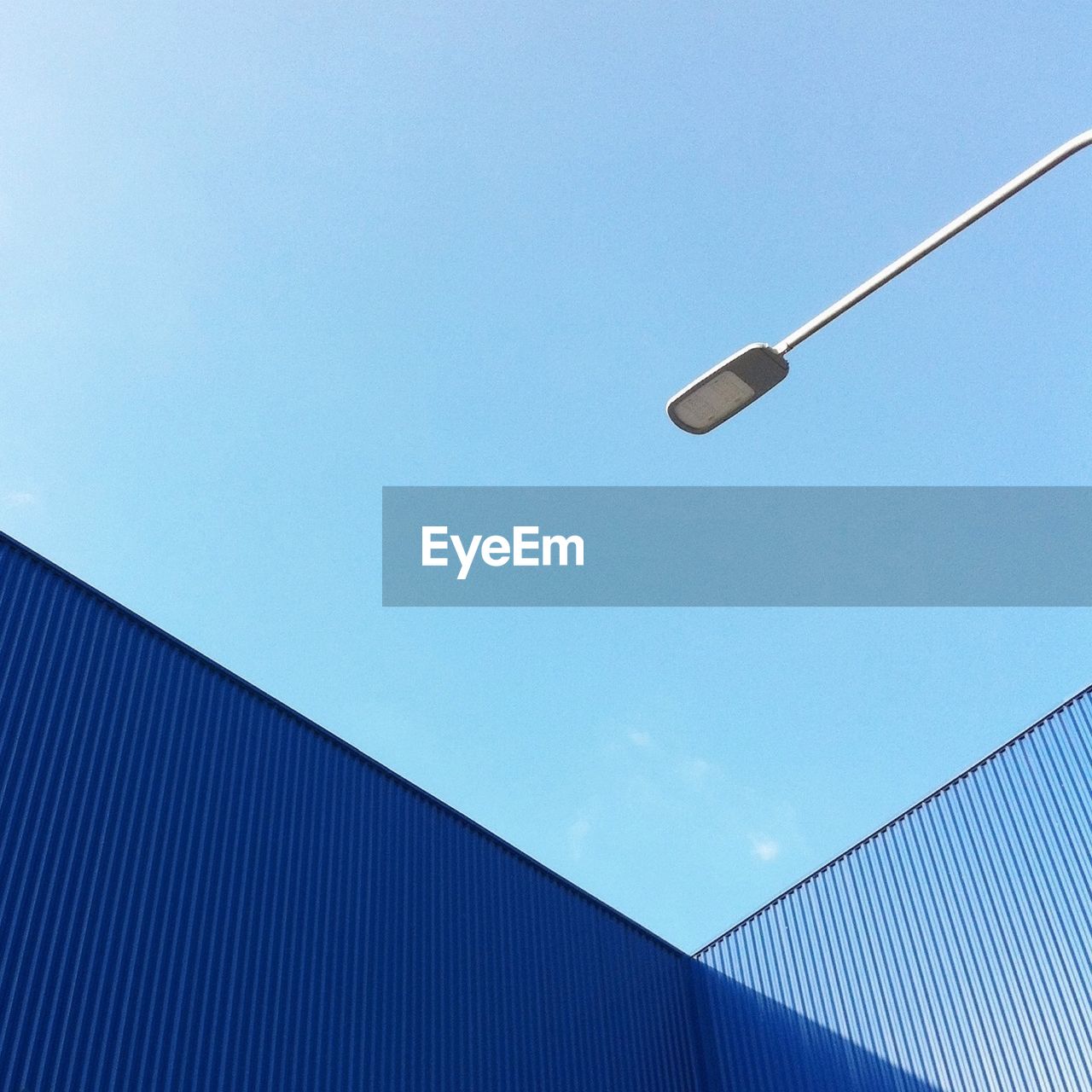 Low angle view of cargo containers and lighting equipment against sky