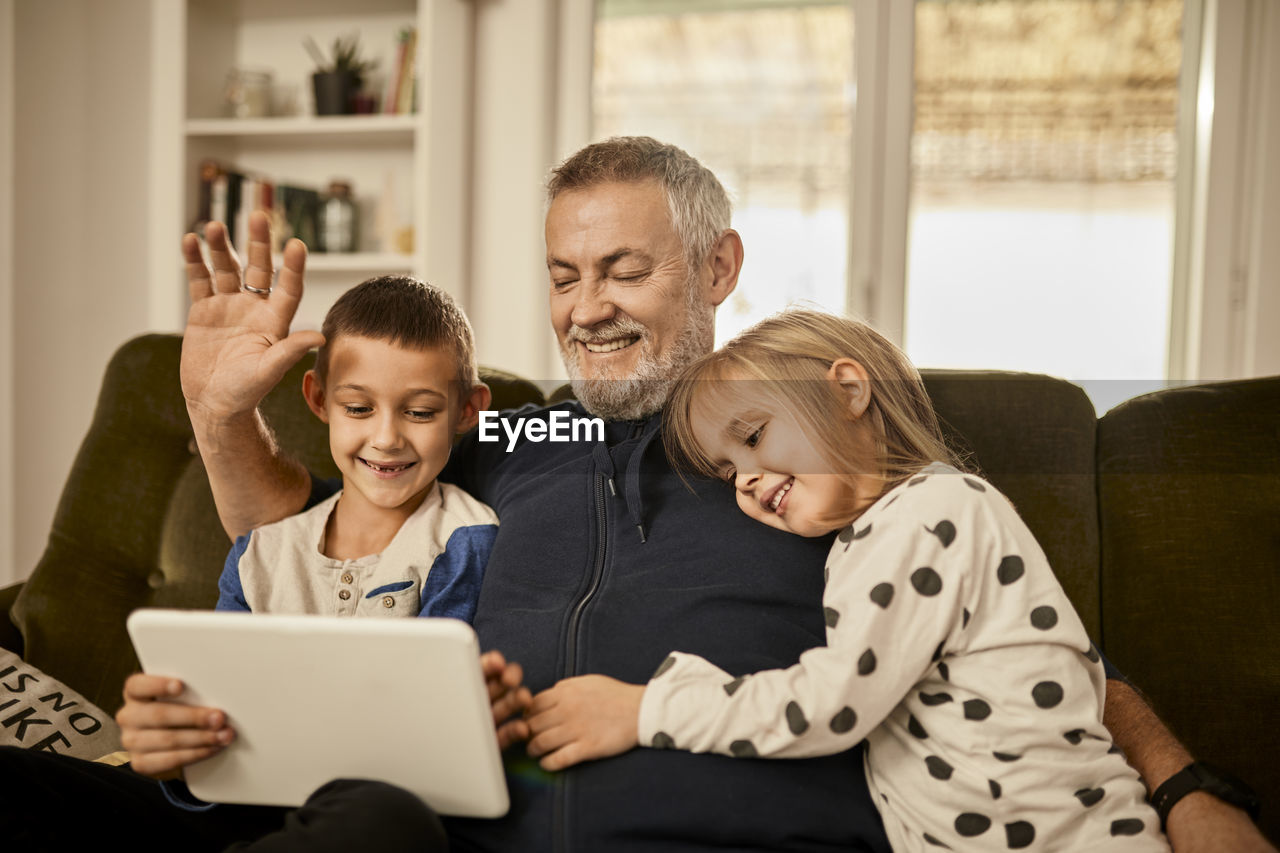 Grandchildren using tablet pc with grandfather at home