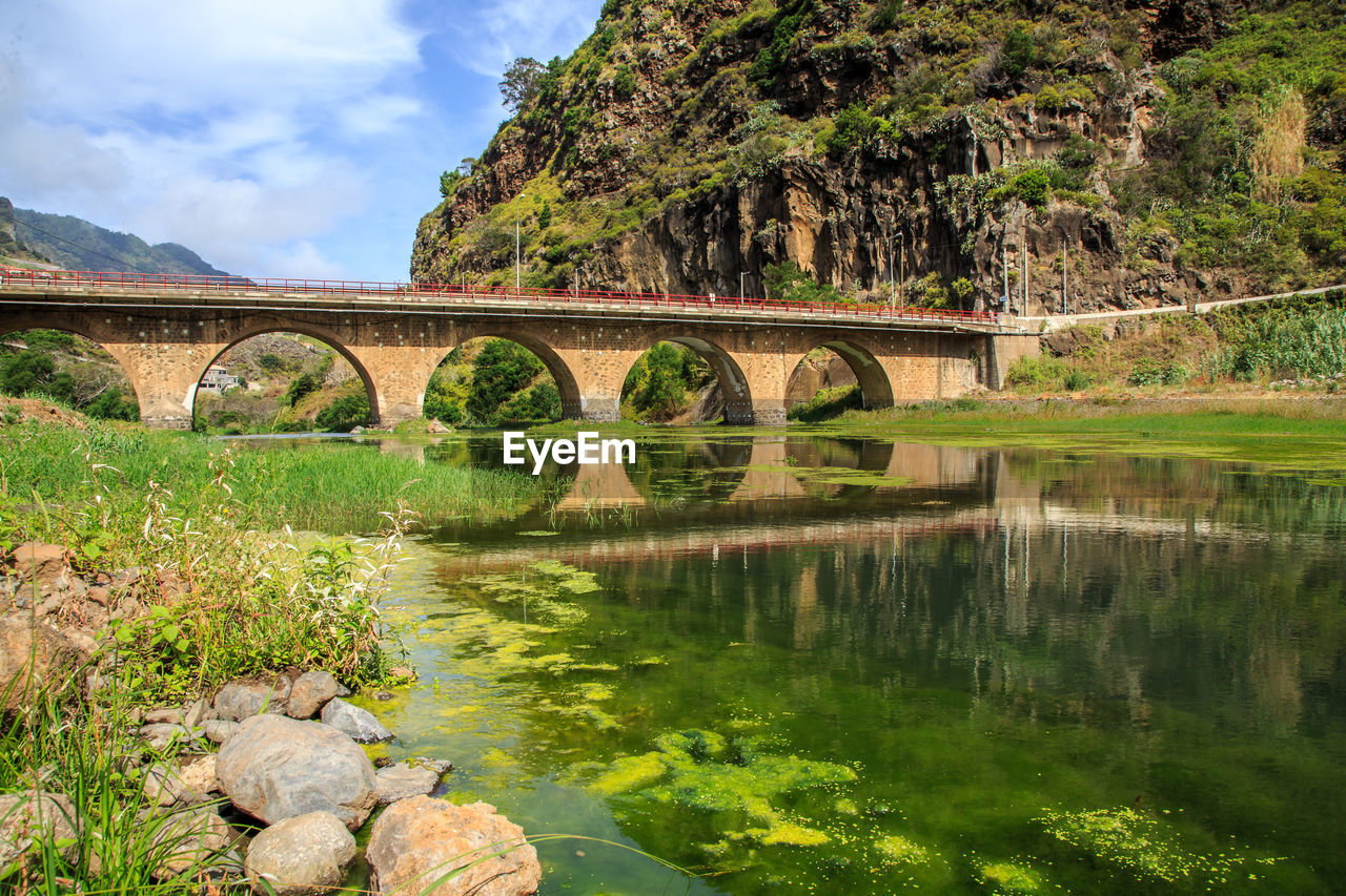 Arch bridge over river against sky