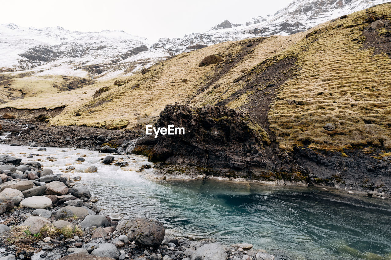 SCENIC VIEW OF SEA AGAINST MOUNTAINS