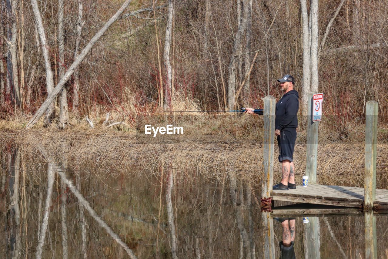 MAN STANDING ON FIELD BY LAKE