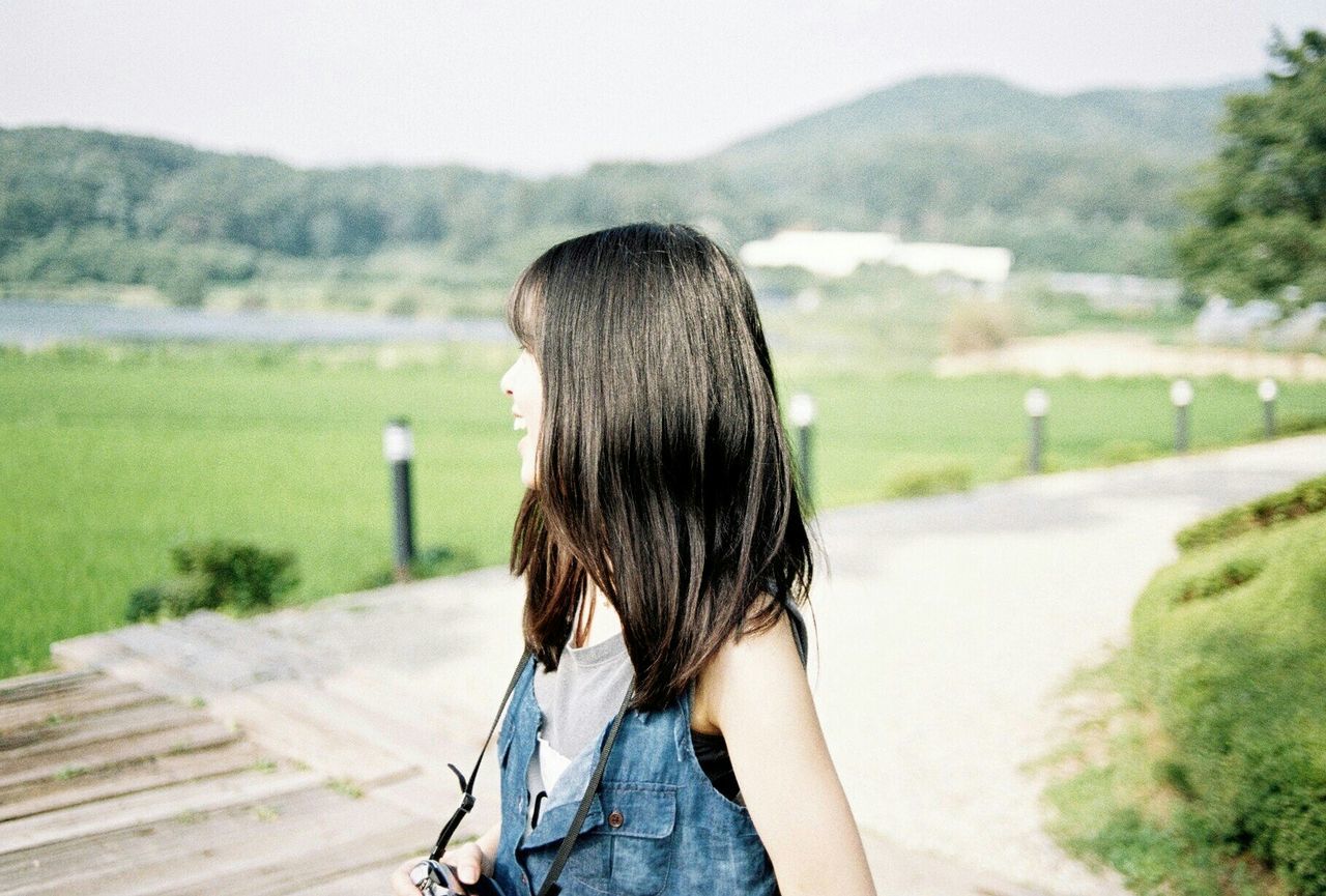 WOMAN STANDING ON GRASSY FIELD