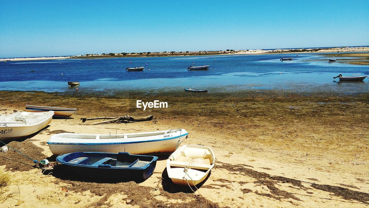 BOATS MOORED ON SEA SHORE AGAINST SKY