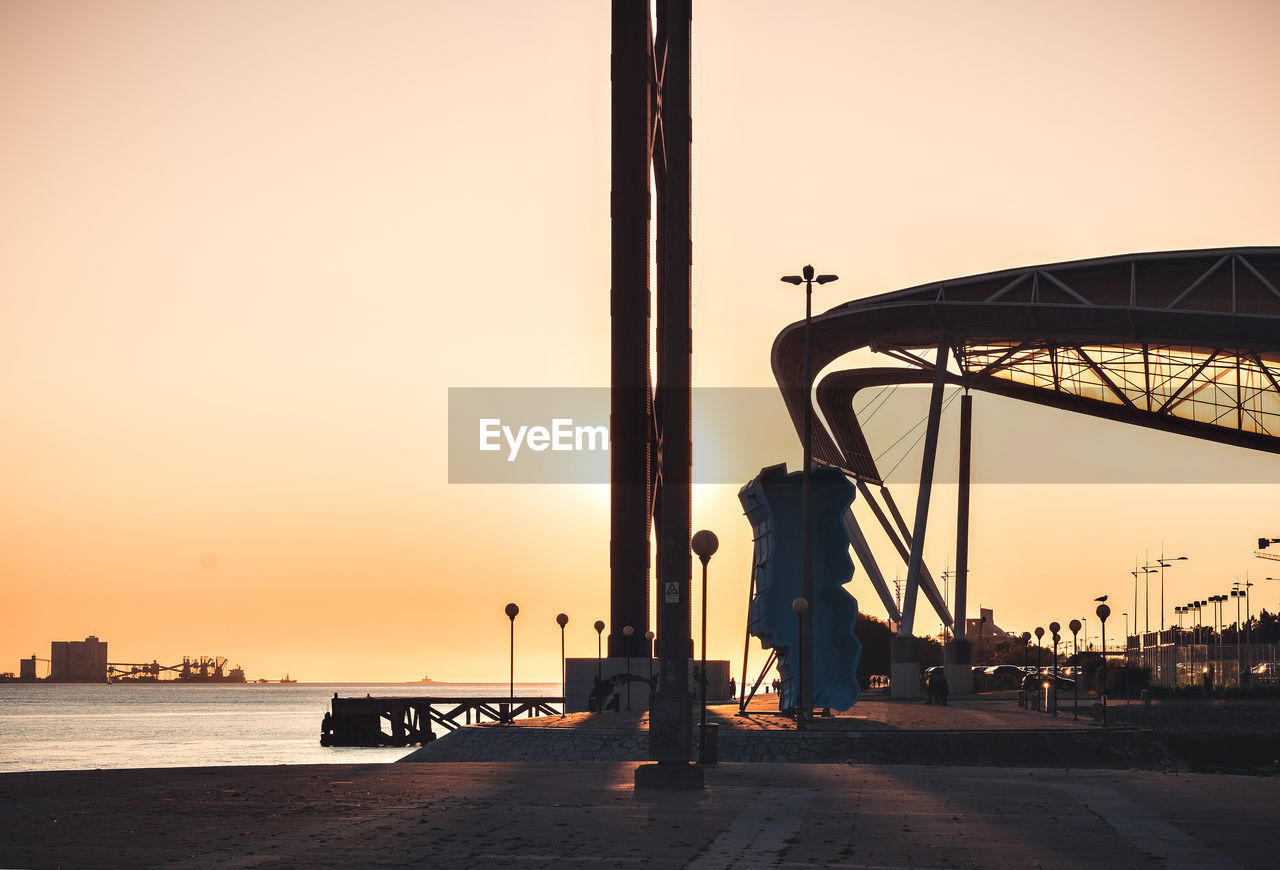 Silhouette man standing on pier by sea against sky during sunset