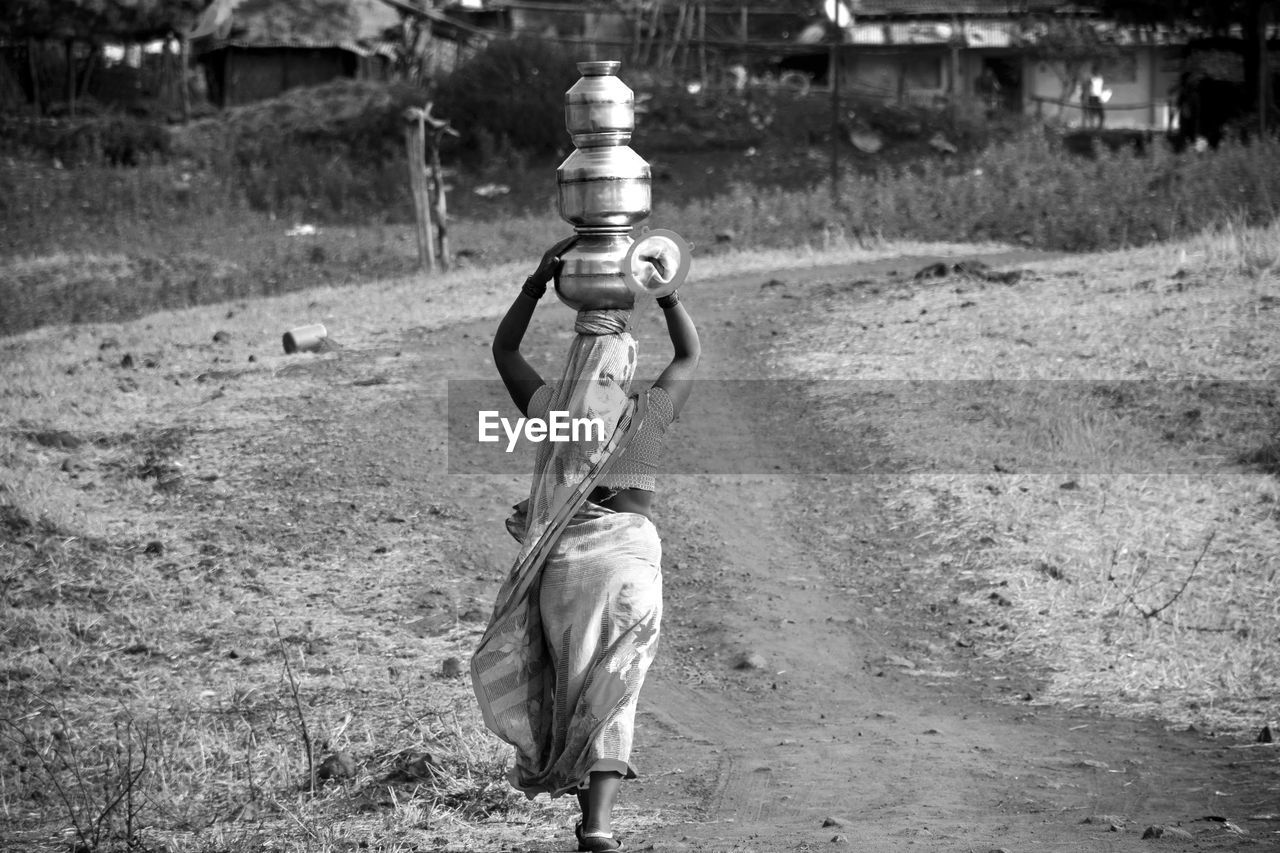 Rear view of woman working on footpath