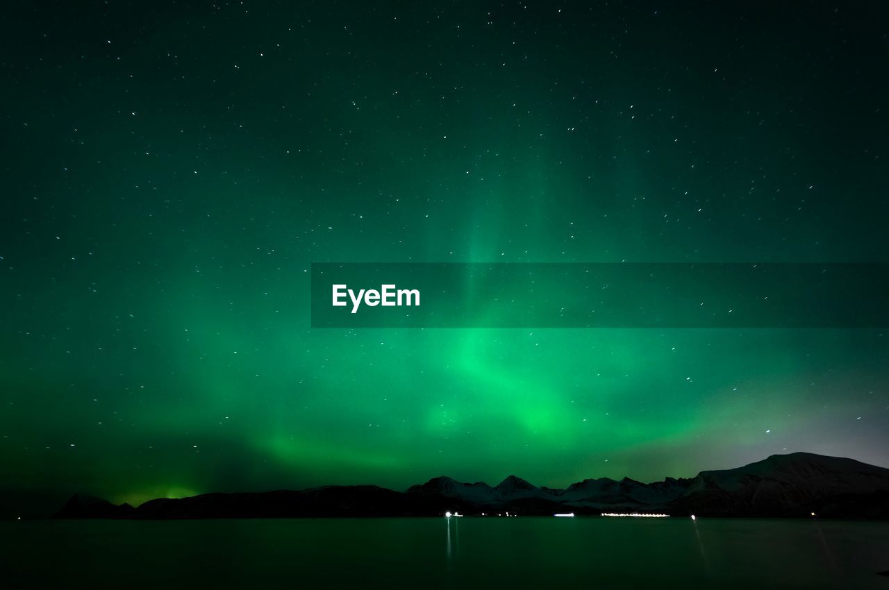 Scenic view of lake and mountains against sky at night