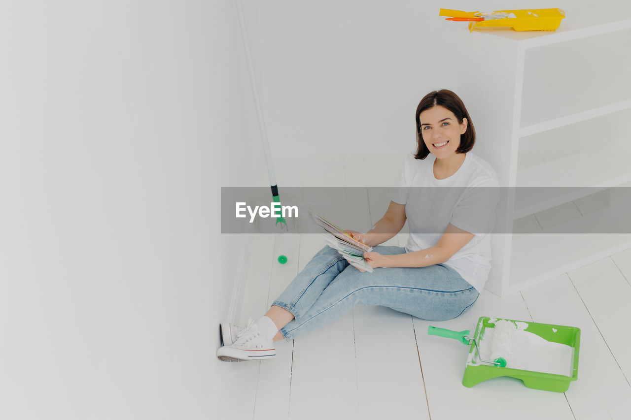 Portrait of smiling woman holding swatch while sitting at new home