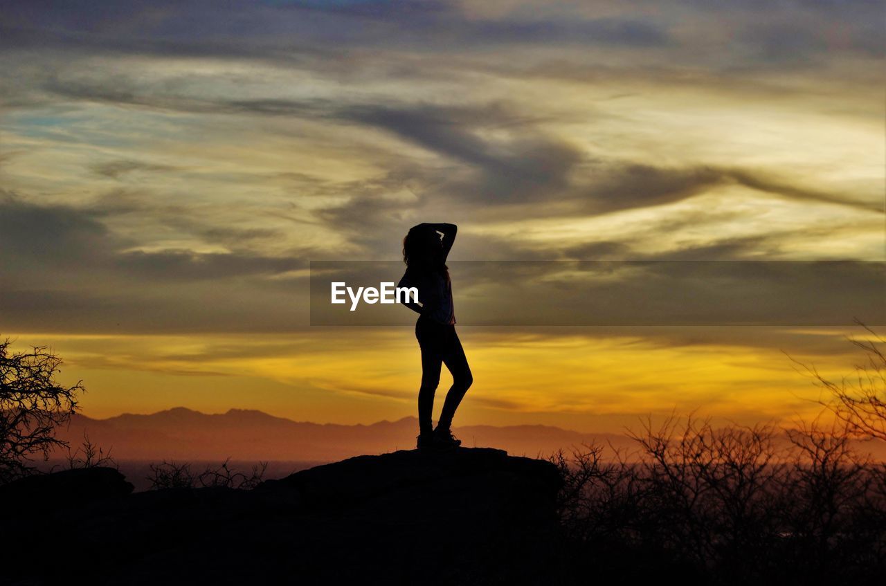 rear view of silhouette man standing on field against sky during sunset