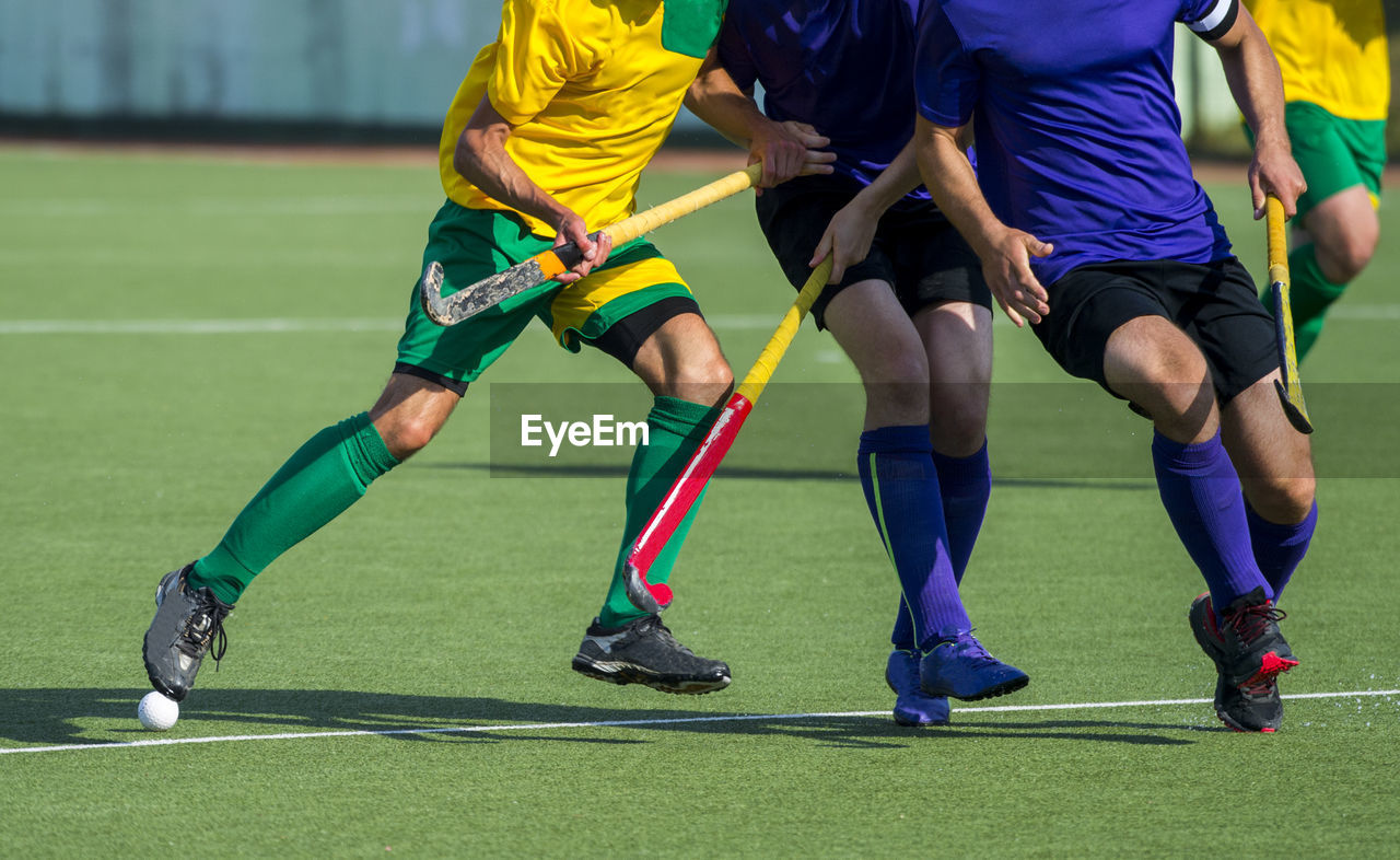 Low section of men playing hockey on turf