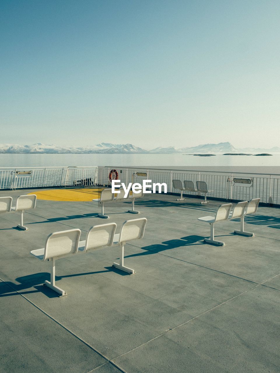 Empty seats on promenade against clear sky