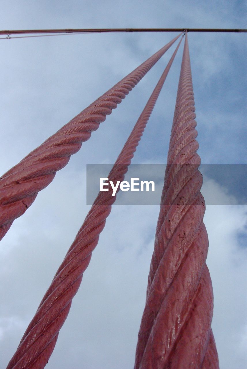 Low angle view of steel cables against cloudy sky