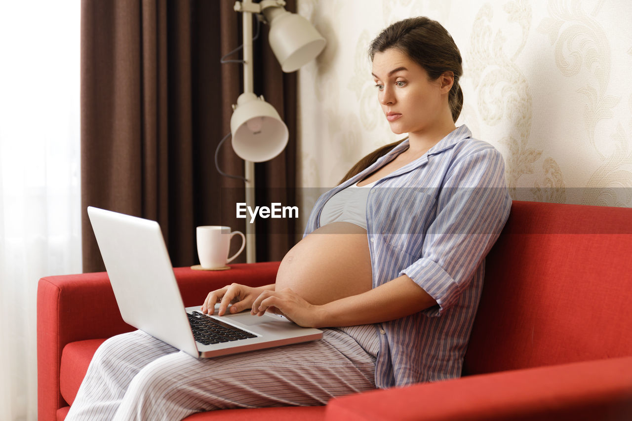Smiling pregnant woman using laptop in office