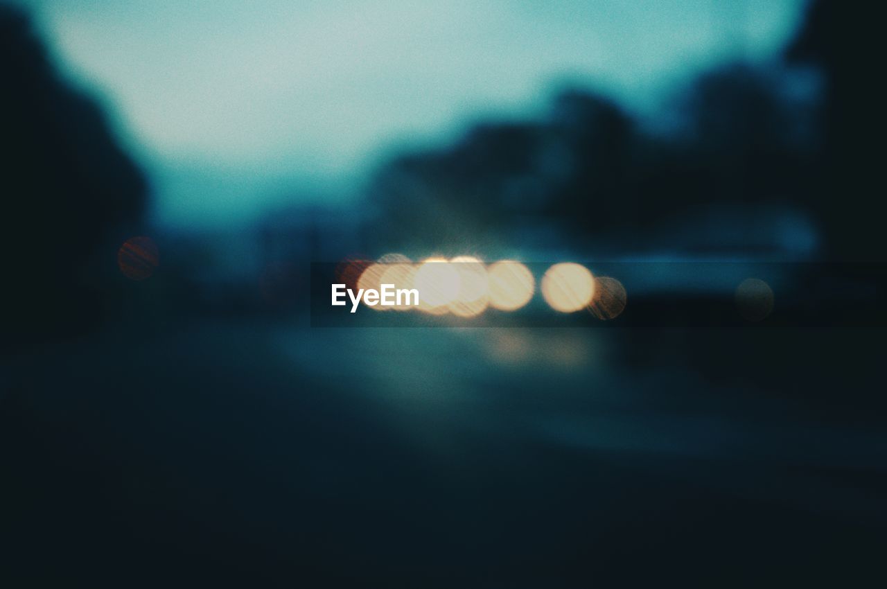 Defocused image of illuminated lights on street at night