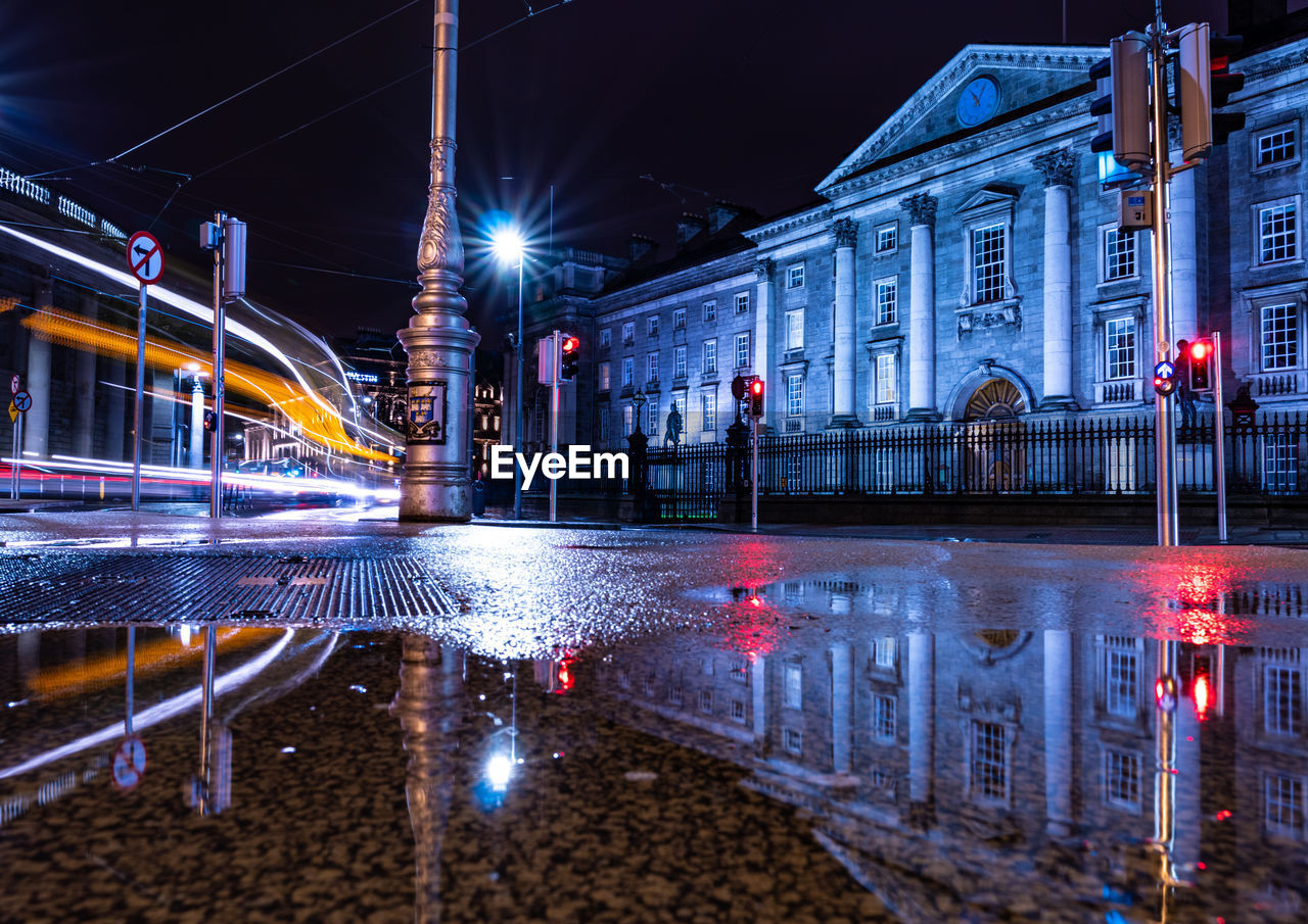 Reflection of buildings in puddle at night