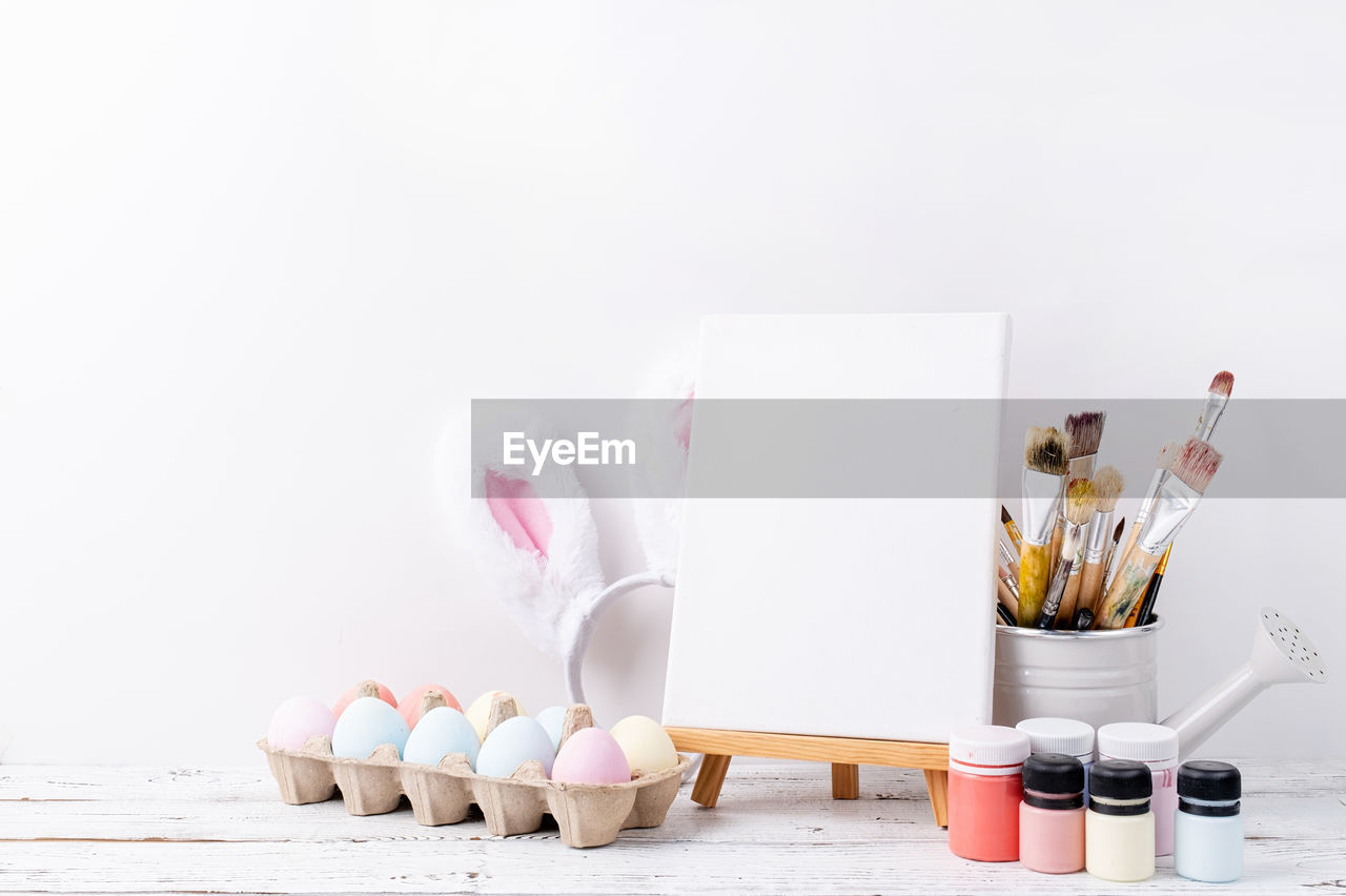 Pastel colored easter eggs and mimosa flowers with blank white frame for mockup design, front view