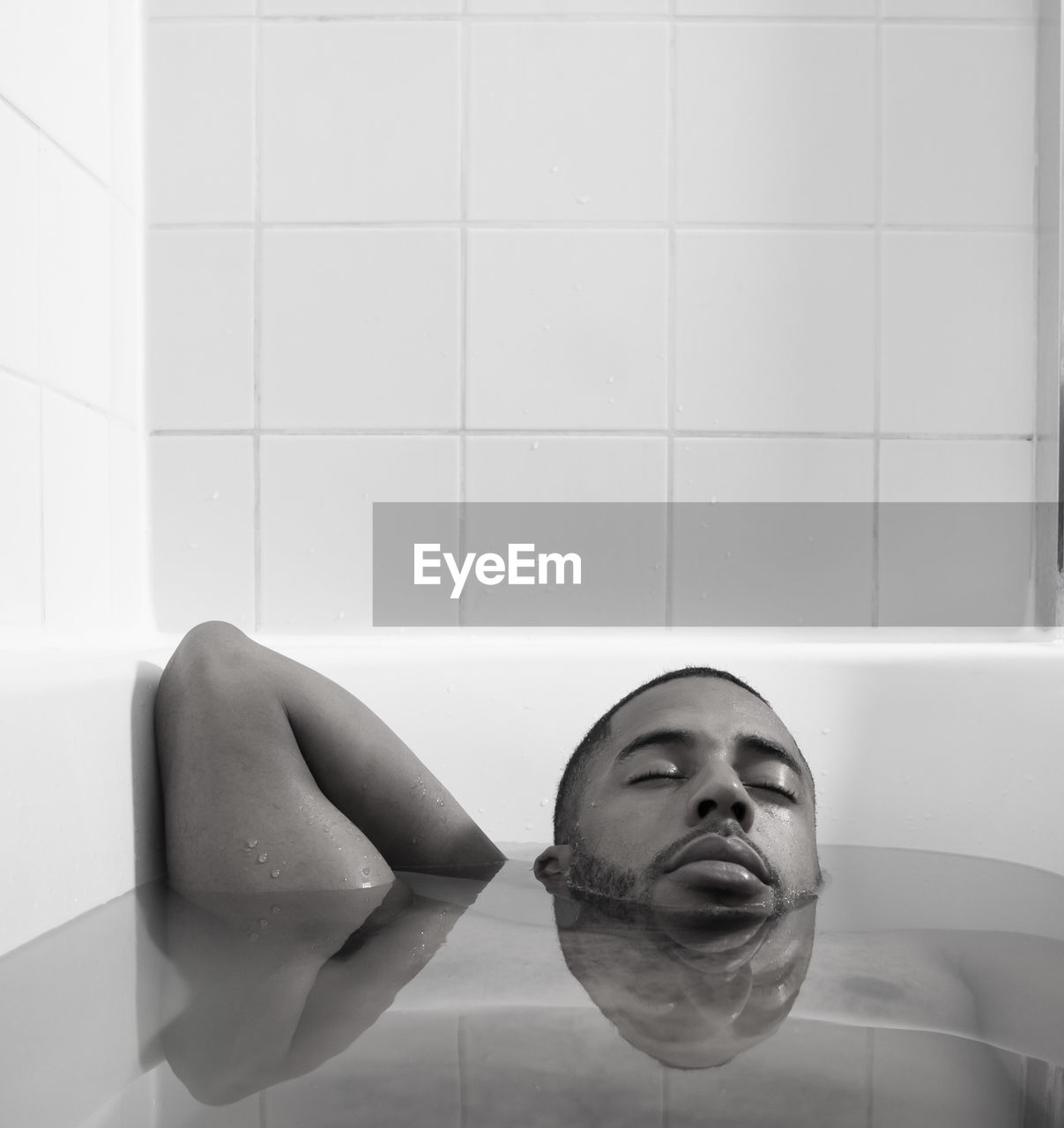 Man with eyes closed relaxing in bathtub