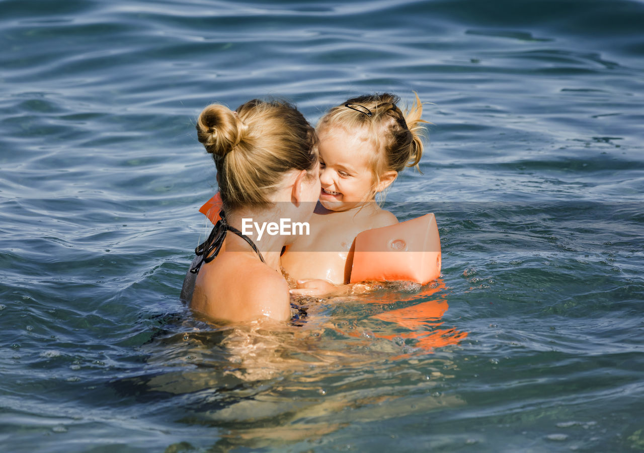 Mother enjoying with daughter in sea during summer