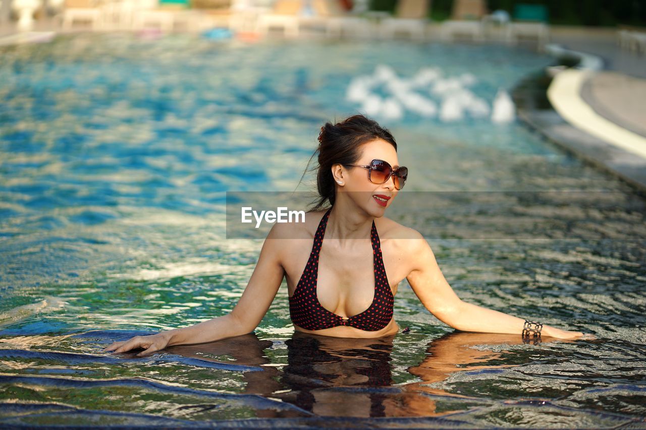 Smiling mature woman wearing sunglasses in swimming pool