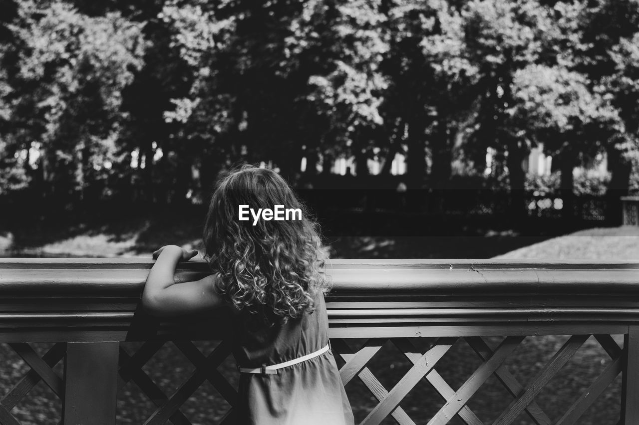 Rear view of girl standing against railing