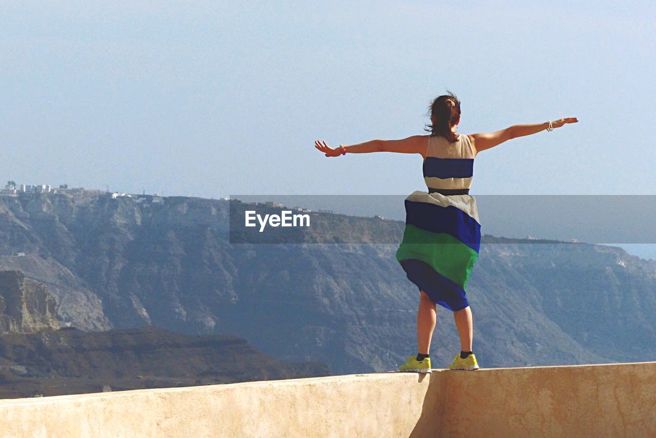 A woman with a dress engages the view of santorini island