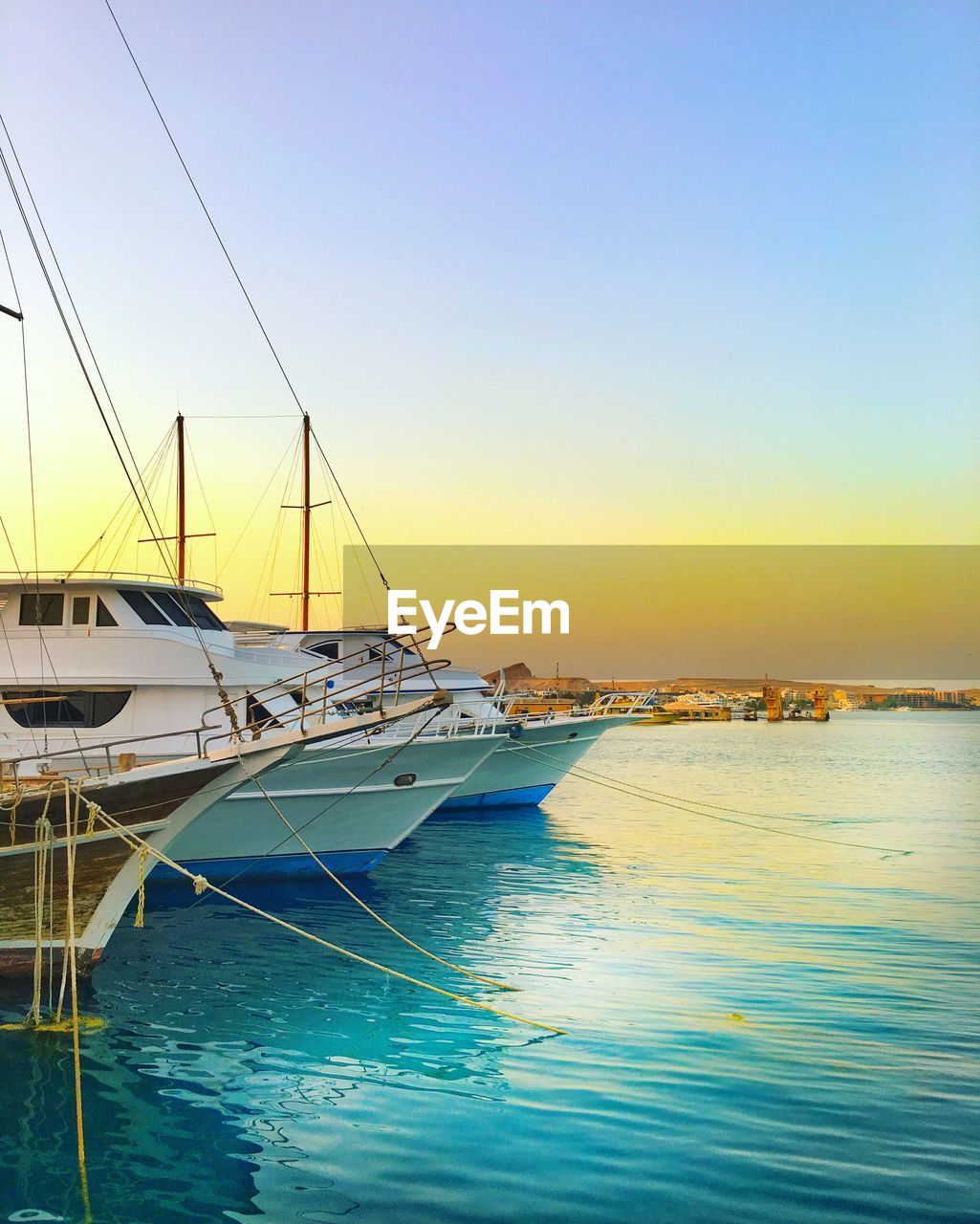 BOATS MOORED IN SEA AGAINST CLEAR SKY