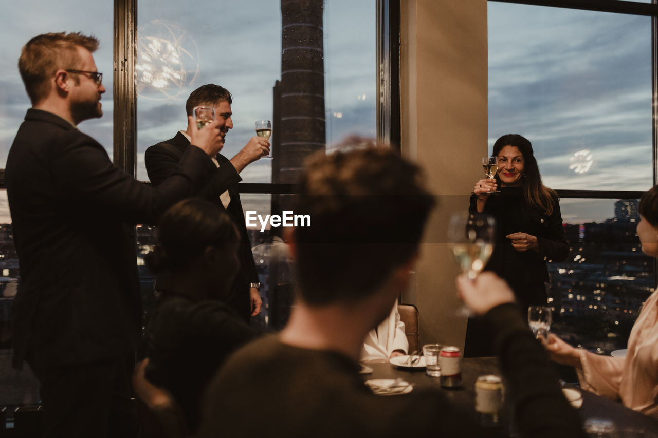 Female and male coworkers toasting while celebrating in office during party