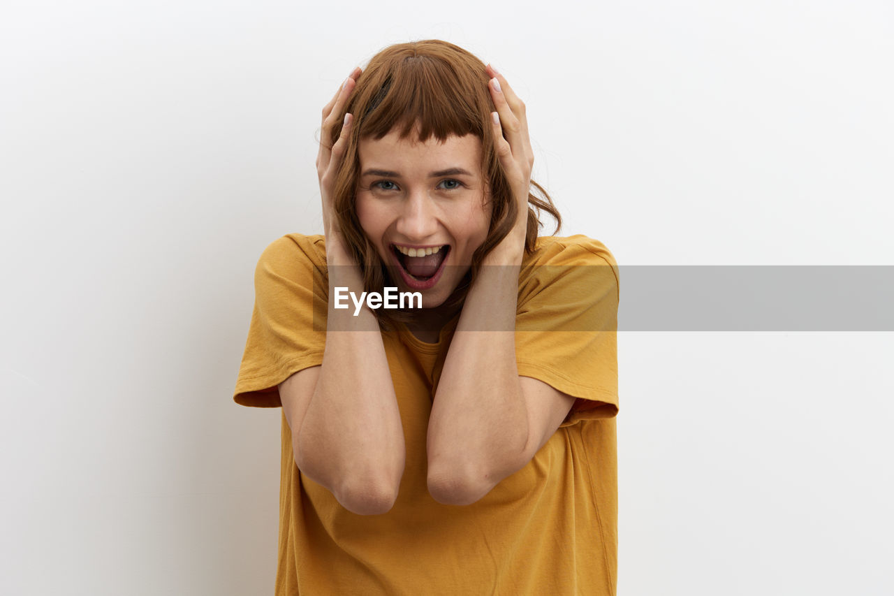 studio shot, emotion, portrait, one person, indoors, adult, yellow, women, young adult, white background, mouth open, looking at camera, negative emotion, clothing, front view, shouting, human face, person, facial expression, copy space, human mouth, casual clothing, hairstyle, waist up, happiness, frustration, smiling, cut out, anger, female, photo shoot, positive emotion, surprise, brown