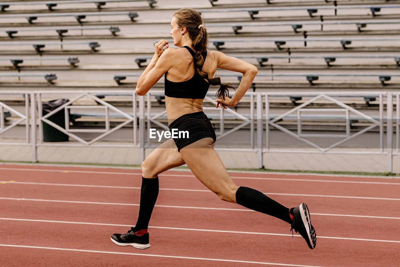 full length of young woman exercising on playing field